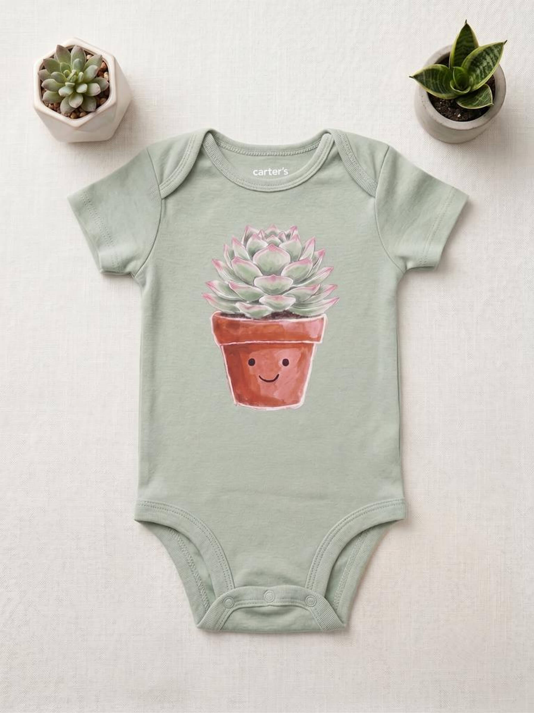 Sage green baby onesie with a potted plant design on a light gray background