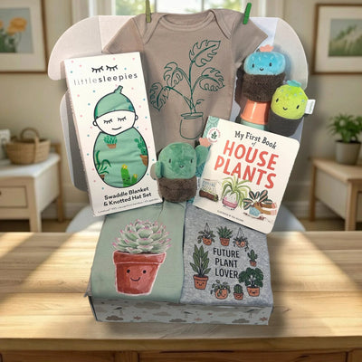 Baby gift set with t-shirt, blanket, books, and plush toys featuring house plants on a wooden surface.