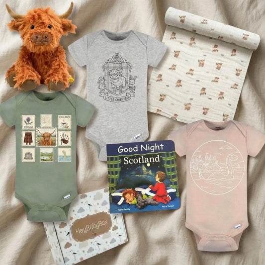 Collection of baby items including onesies, a plush toy, and a book on a beige surface