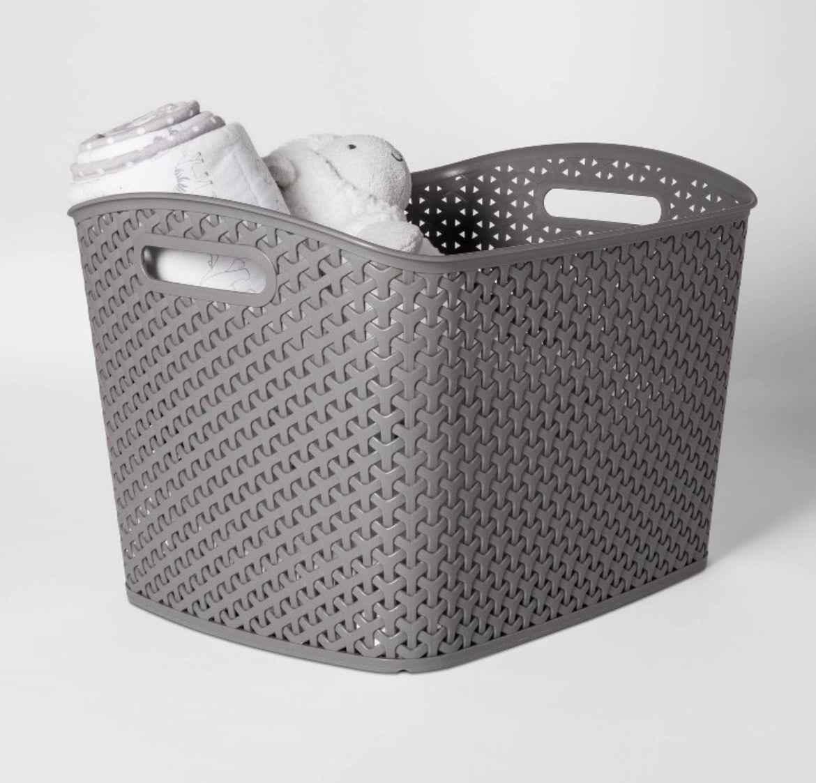 Gray woven storage basket with baby blanket and plush toy, ideal for nursery organization