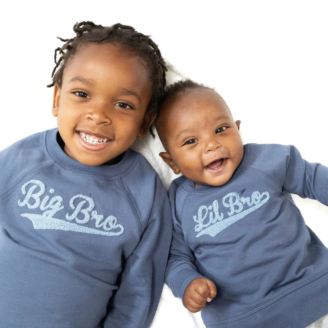 Two children wearing matching blue sweatshirts with 'Big Bro' and 'Lil Bro' text on a white background.