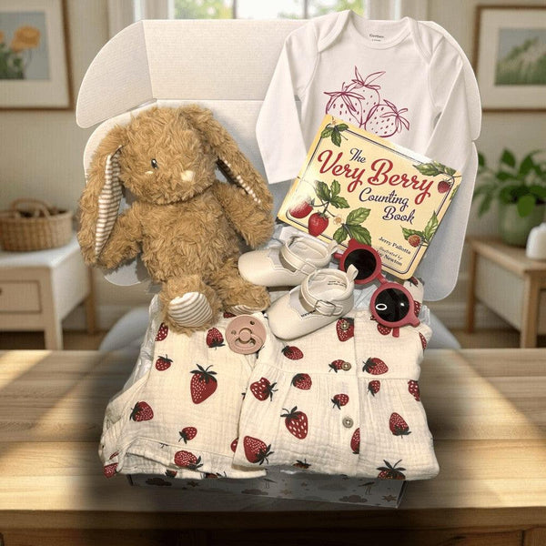 Hey Baby Box strawberry theme baby girl gift set with muslin clothes, onesie, shoes, sunglasses, pacifier, plush bunny, and book.