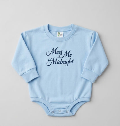 Light blue baby onesie with 'Meet Me at Midnight' text on a gray background