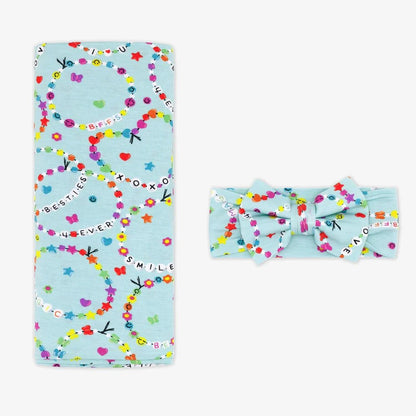 Light blue blanket with colorful patterns and a matching headband on a white background little sleepies
