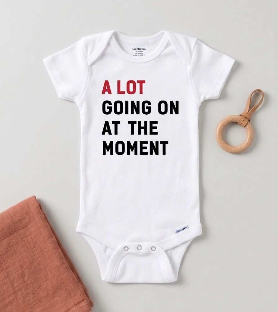 White baby onesie with text and a wooden toy on a light gray background