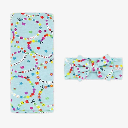 Light blue blanket with colorful patterns and a matching headband on a white background little sleepies