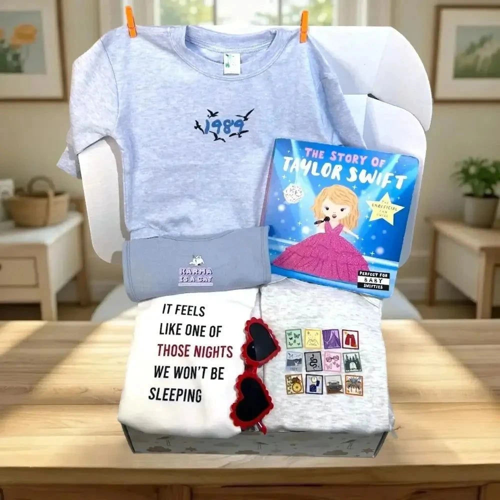 T-shirt with a design, book titled 'The Story of Taylor Swift', and a white pillow with text and sunglasses on a wooden surface.