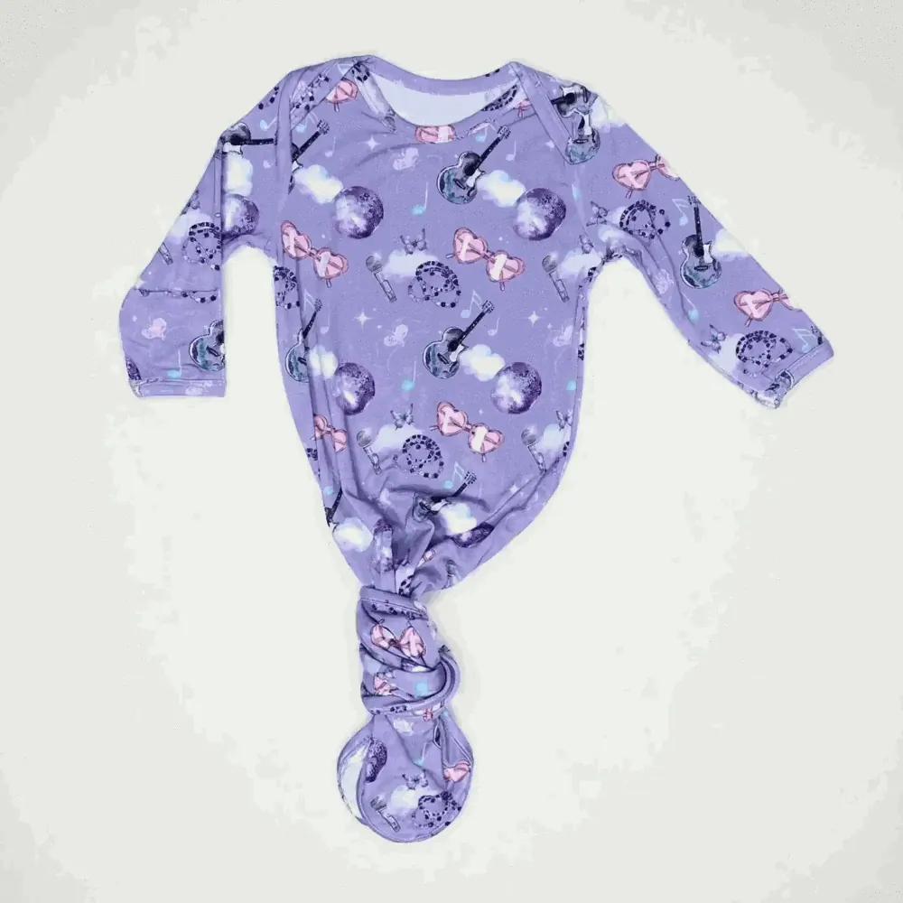 Purple baby onesie with music-themed design on a white background