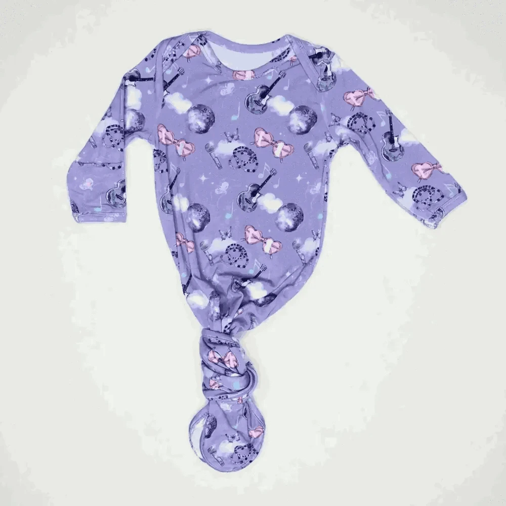 Purple baby onesie with music-themed design on a white background