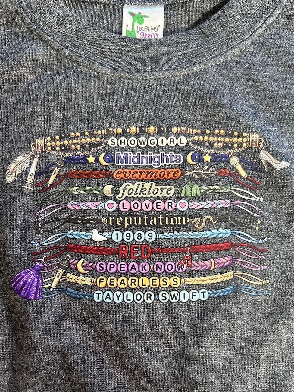 Gray sweatshirt with colorful embroidered text and designs on a dark background