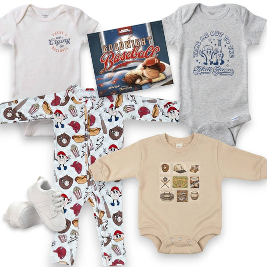Collection of baby clothing and a book with baseball theme on a white background