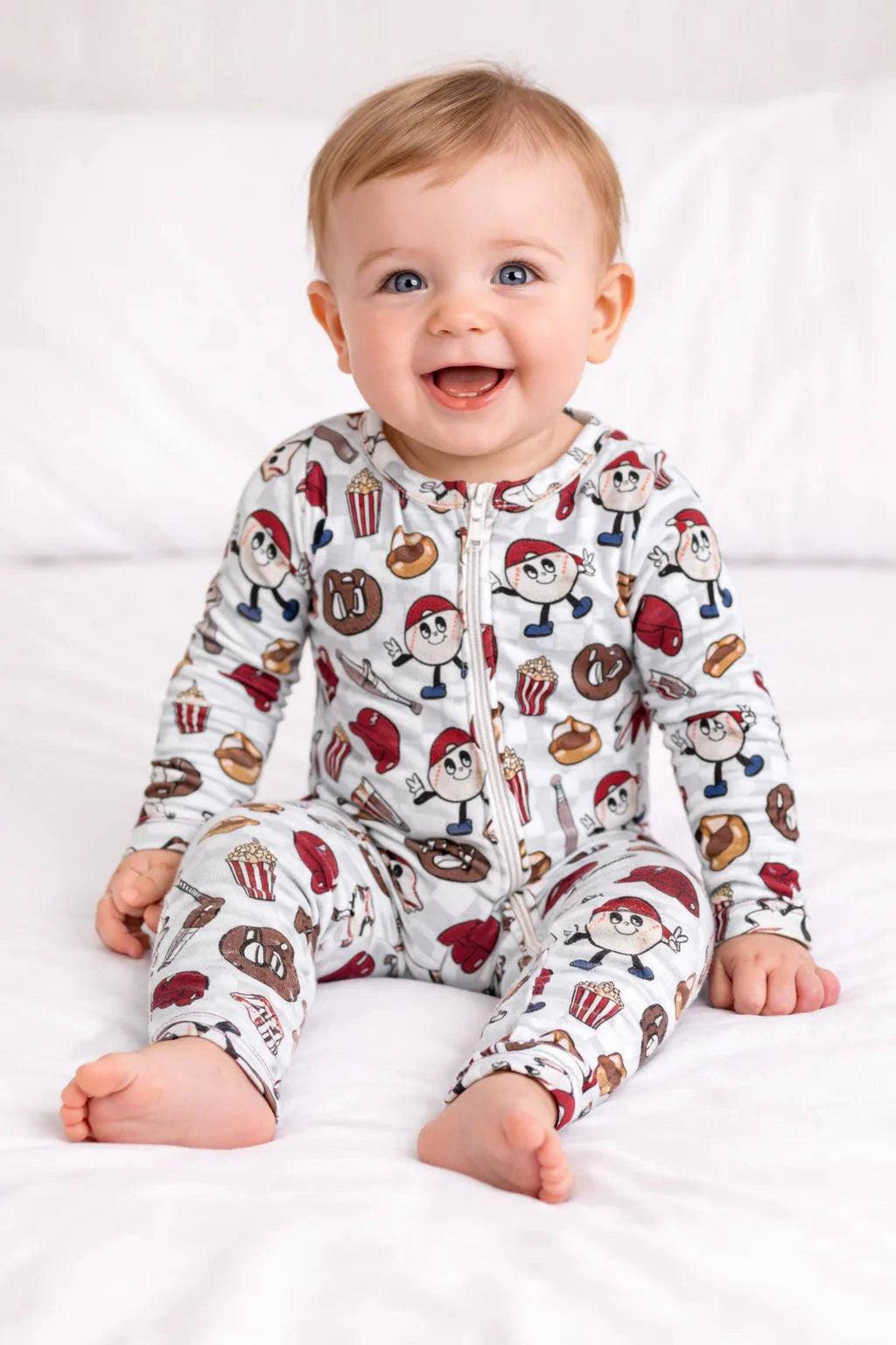 Baby wearing a patterned onesie sitting on a white surface