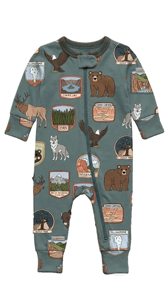 A toddler's long-sleeve footless one-piece sleeper in sage green, featuring an all-over print of national park badges, bears, eagles, wolves, and deer.