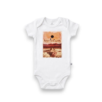 A white short-sleeve baby bodysuit featuring a rectangular graphic print on the chest. The print shows a warm-toned desert landscape with a figure and the text 'Alice in Chains'.
