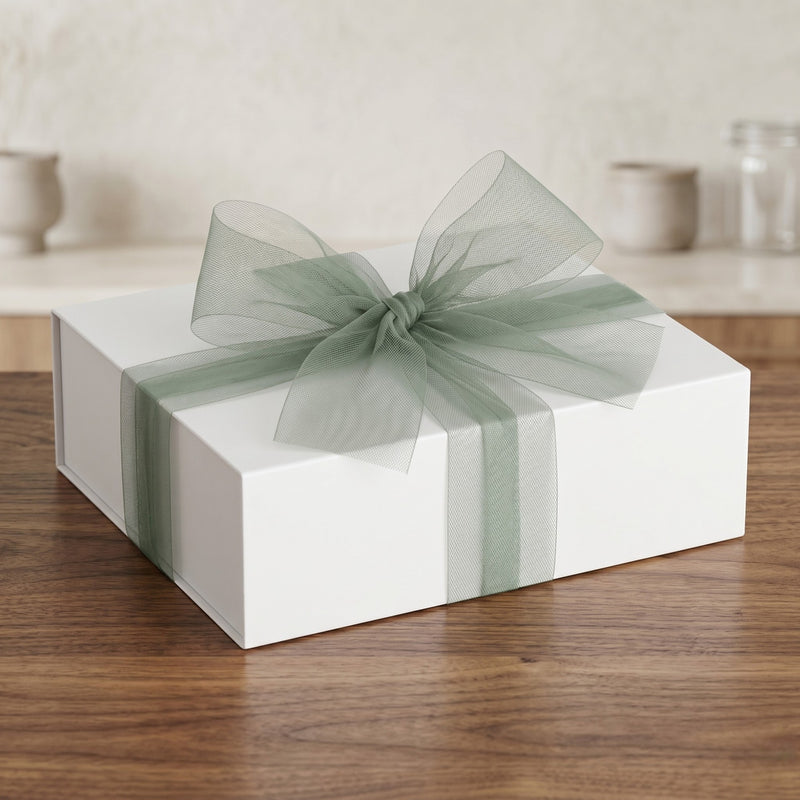 White gift box with a green ribbon on a wooden surface